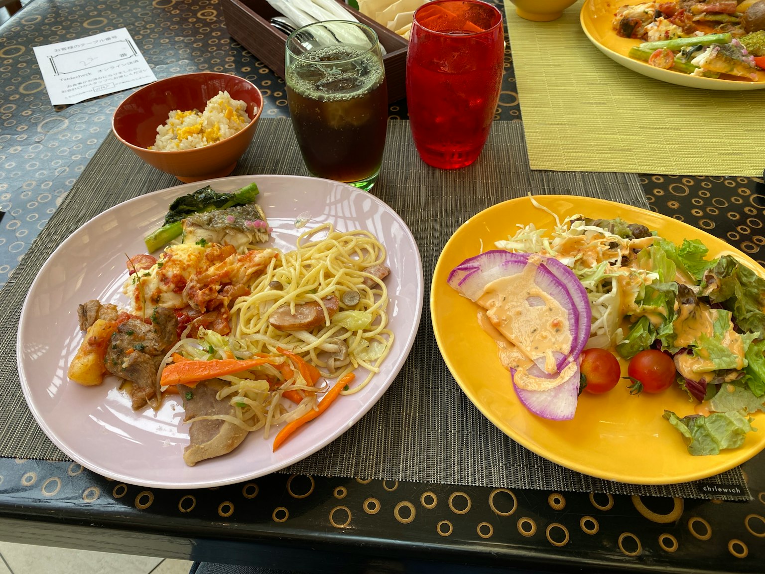 Une table avec des plats colorés incluant des nouilles, des légumes et une salade