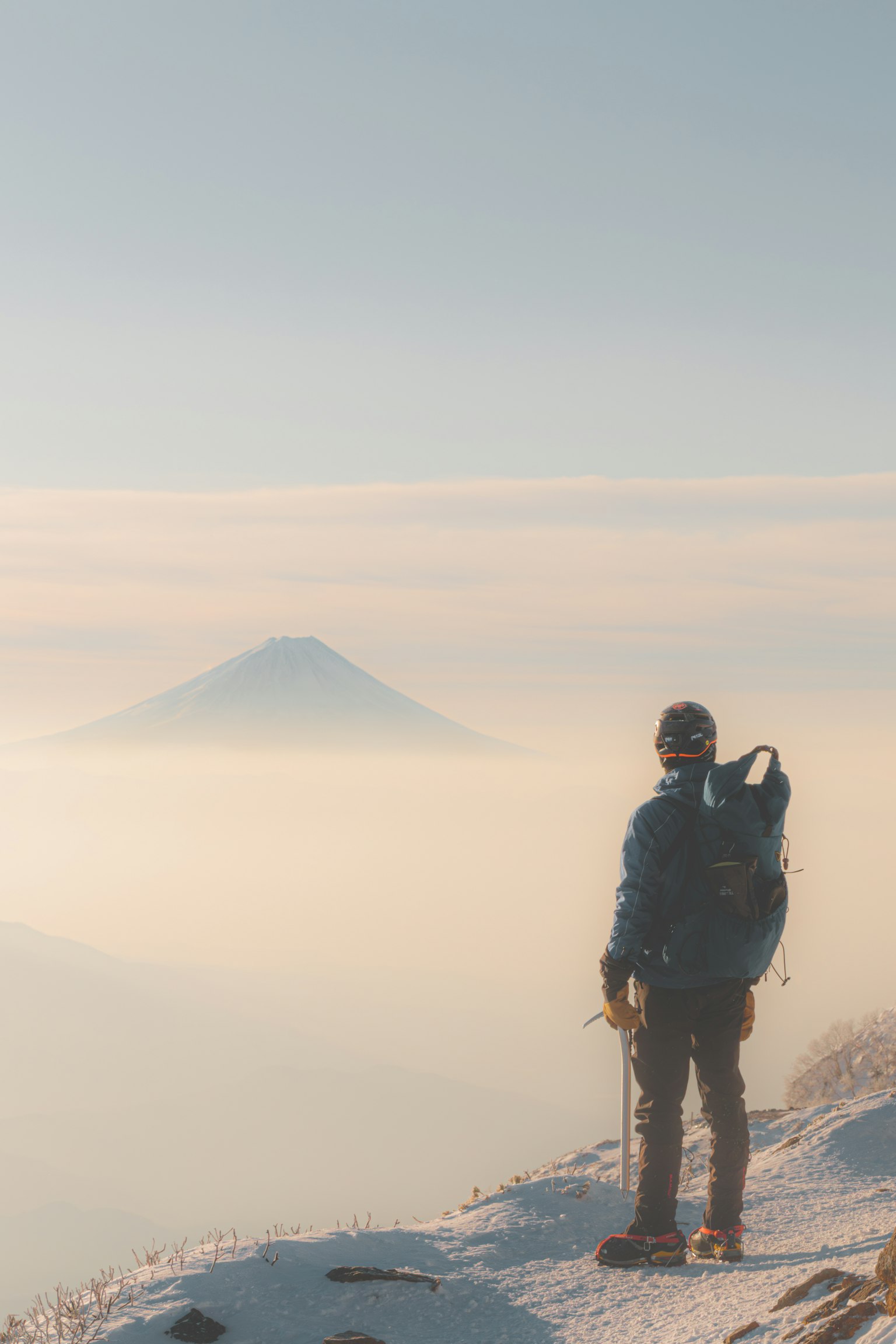 站在雪山顶上的登山者，远处有山的轮廓