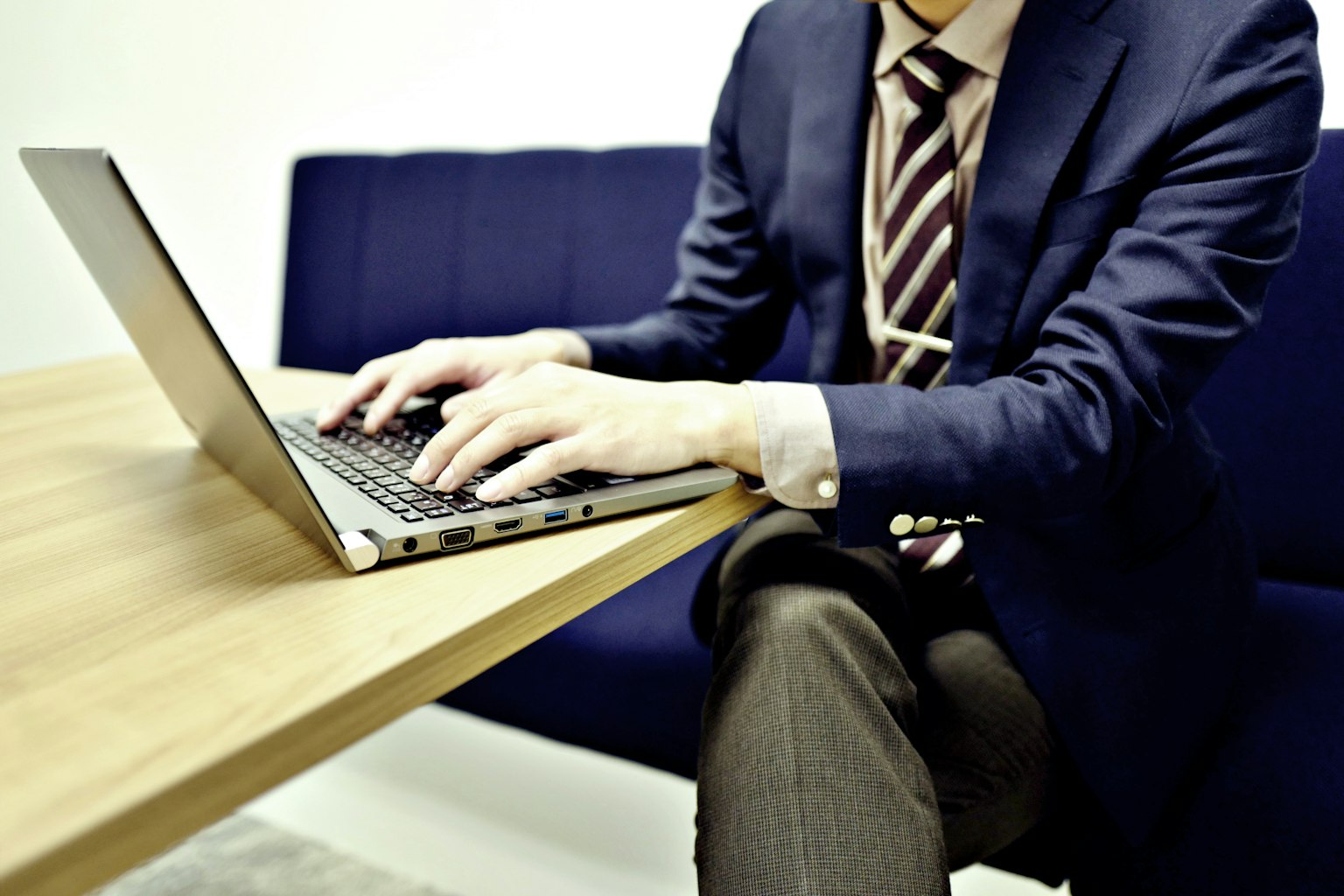 Ein Mann im Anzug, der an einem Tisch einen Laptop benutzt