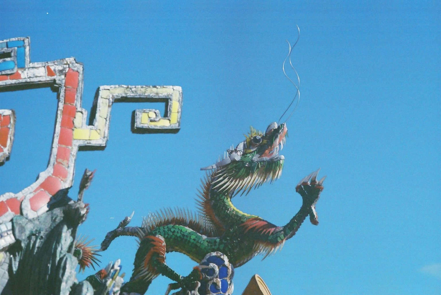 Colorful dragon sculpture spouting water under a blue sky