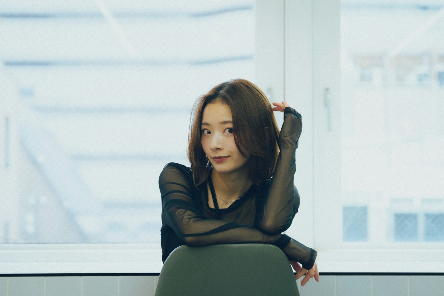 창가에 앉아 있는 여성의 초상화 검은색 상의를 입고 긴 머리를 가지고 있음