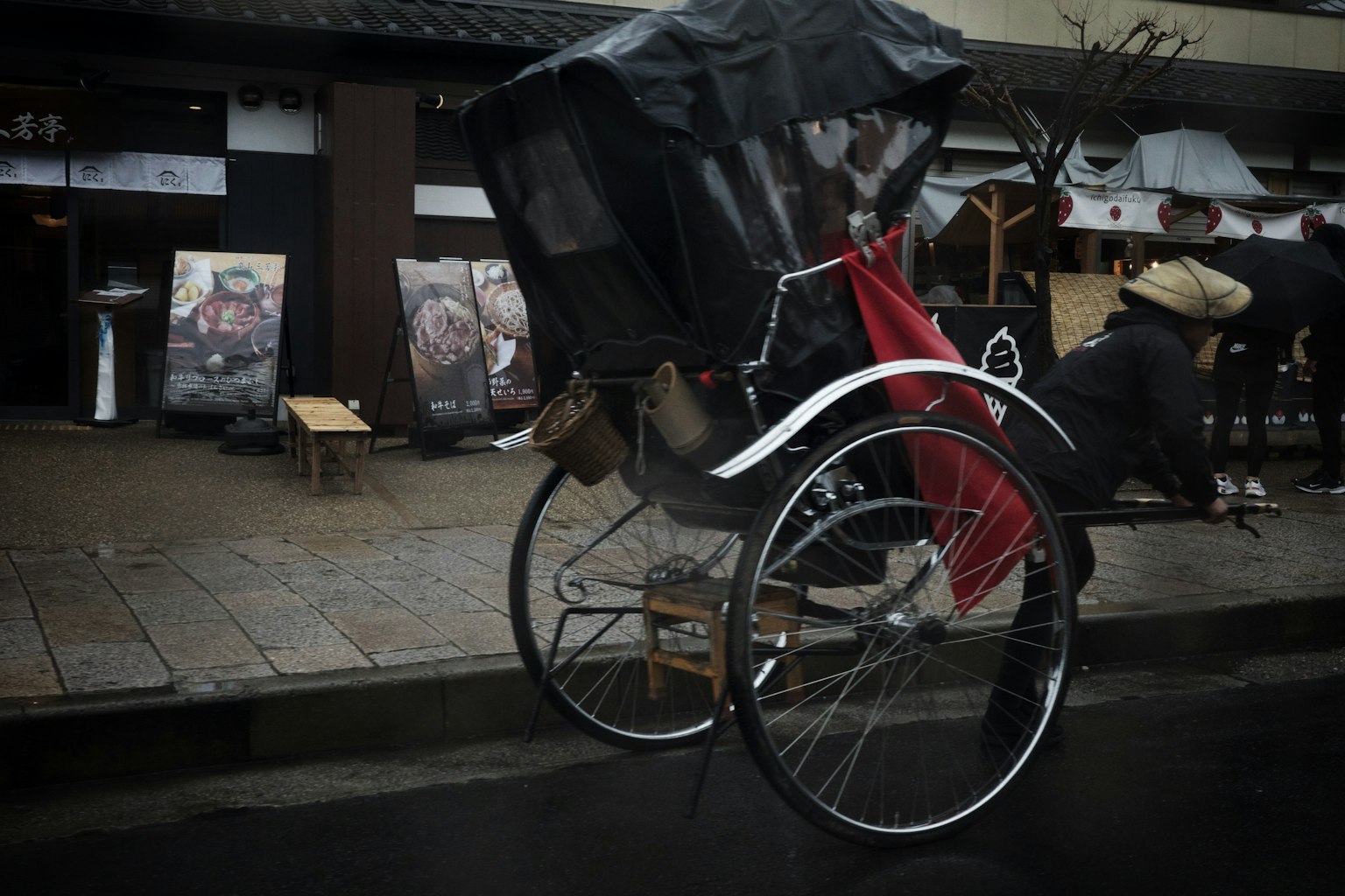 Rickshaw esperando bajo la lluvia con una cubierta negra