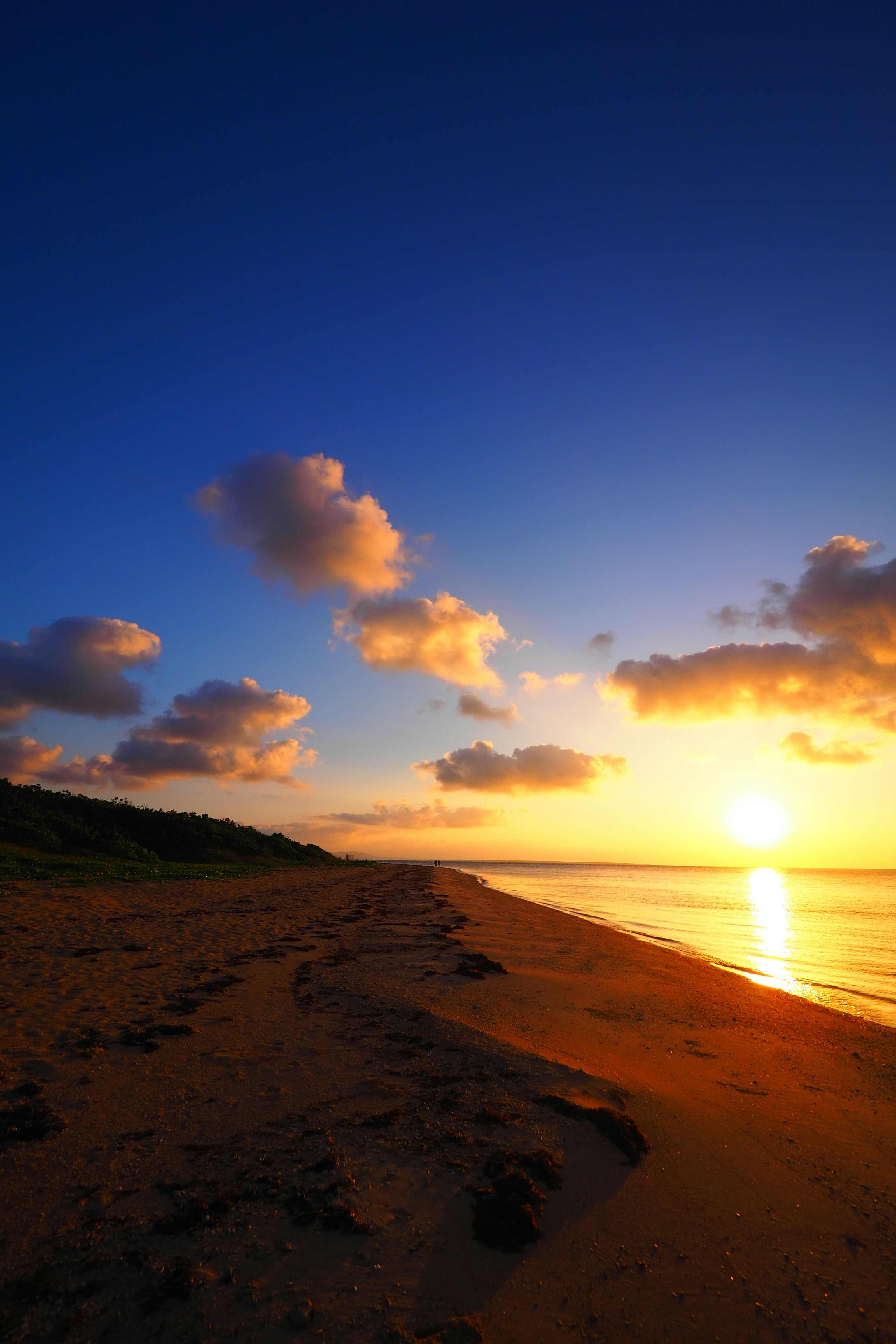 夕日に照らされる海辺の砂浜と雲