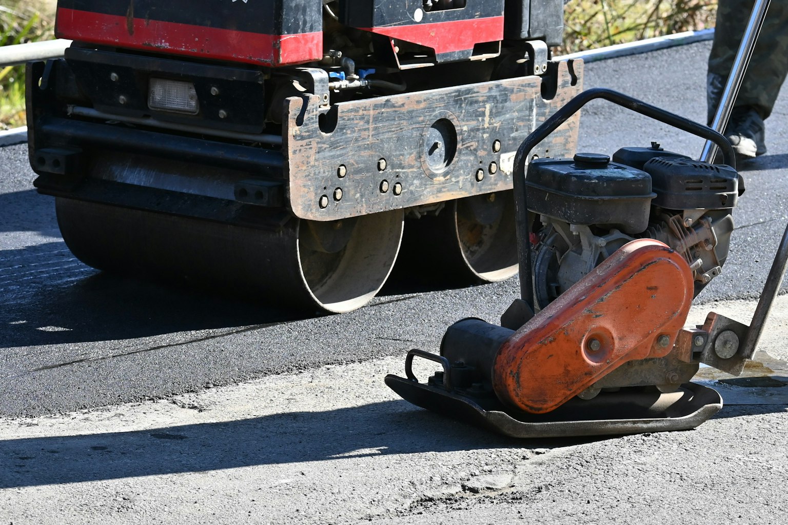 Vibrationsplattenverdichter und Asphaltwalze auf einer Baustelle
