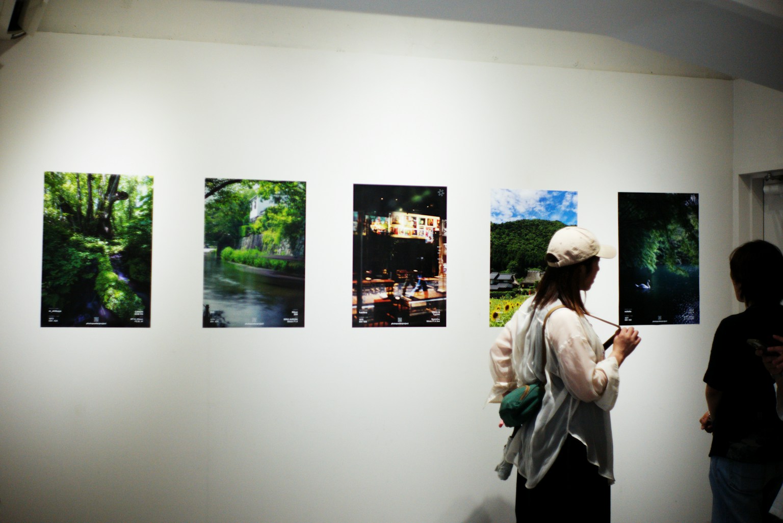 展示された風景写真が並ぶアートギャラリーの内部で観客が鑑賞している