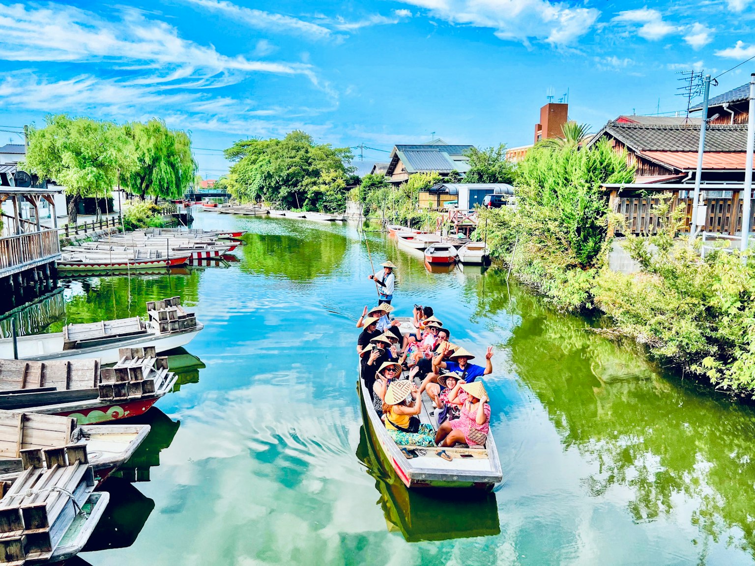 Bateau touristique naviguant sur un canal sous un ciel bleu avec une verdure luxuriante