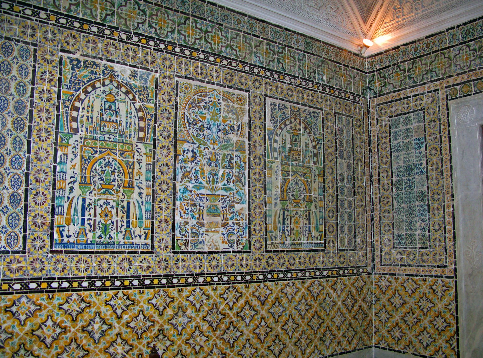Vista interior de una habitación con paredes de azulejos decorativos que muestran patrones vibrantes y diseños tradicionales