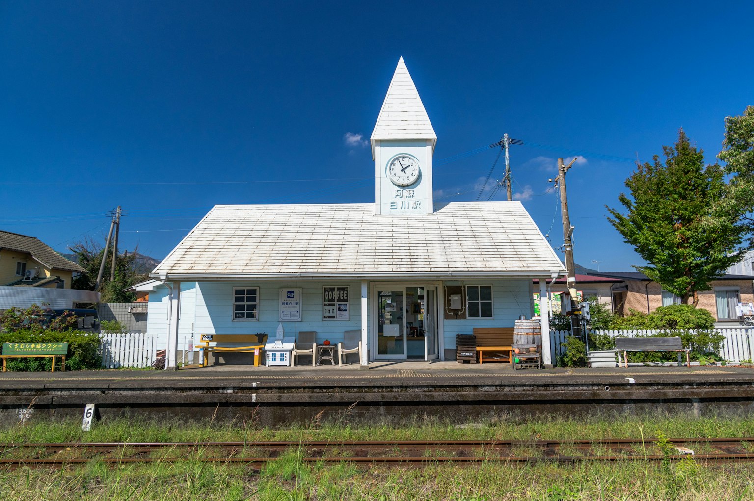 สถานีรถไฟสีขาวที่มีเสน่ห์พร้อมหอระฆังและม้านั่ง