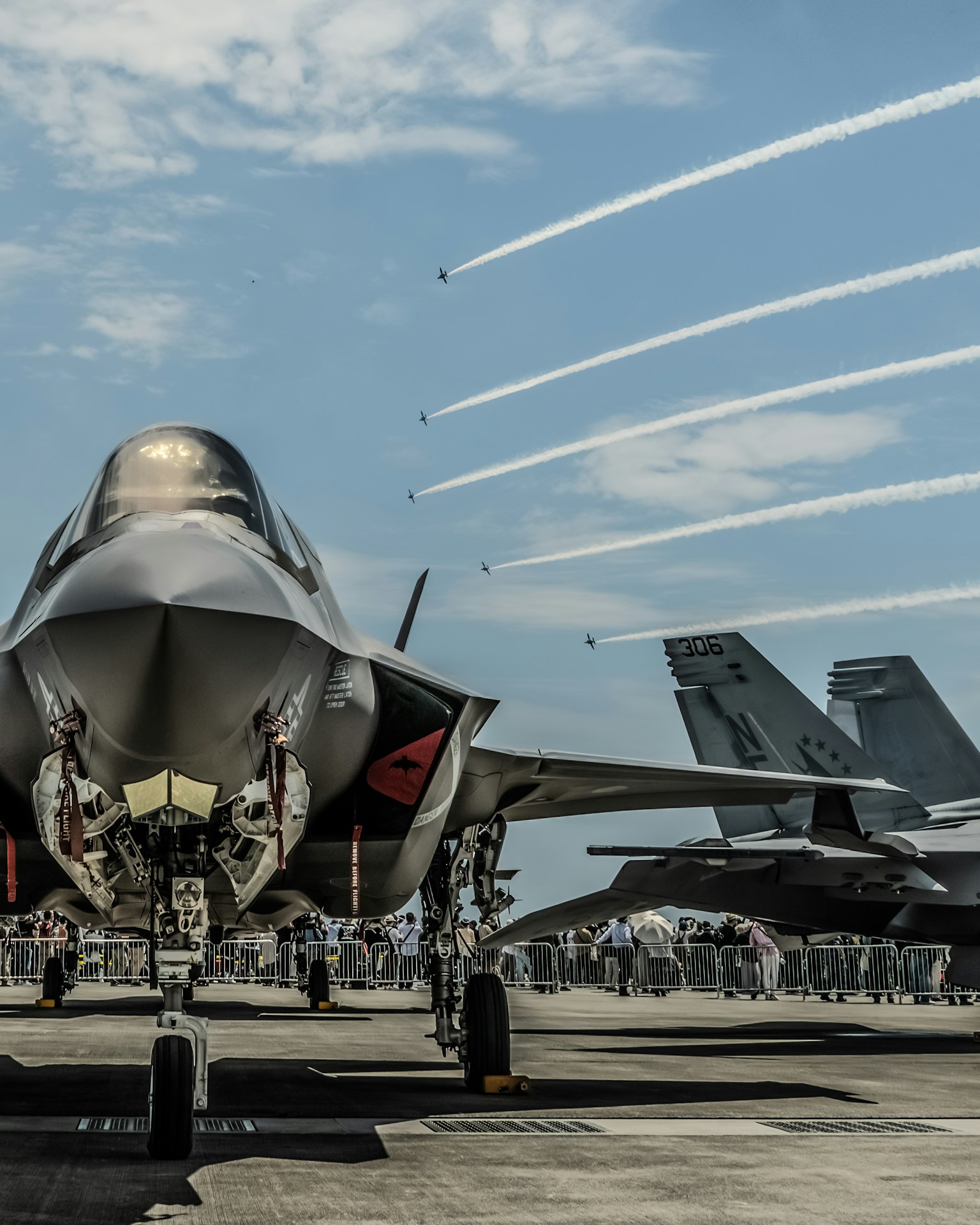 เครื่องบินขับไล่ F-35 บนทางวิ่งที่มีท้องฟ้าสีฟ้าและรอยทางอากาศด้านหลัง