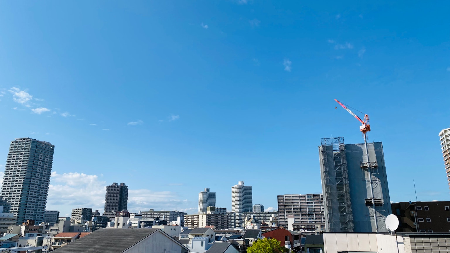 晴空下的城市天际线，展示摩天大楼和建筑起重机
