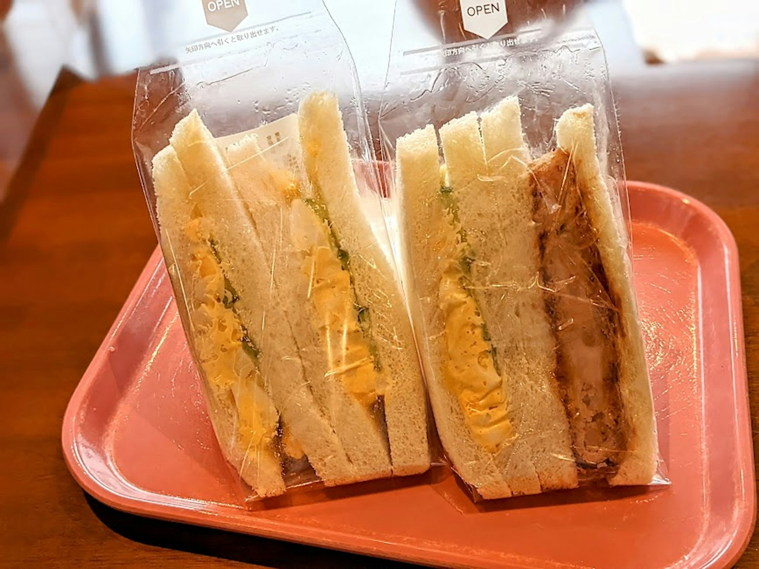 Deux sandwichs dans un emballage transparent sur un plateau rose
