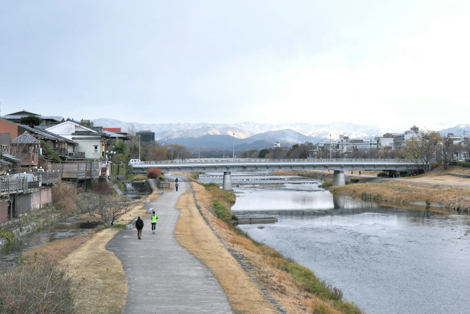 Serene riverside walkway with distant mountains