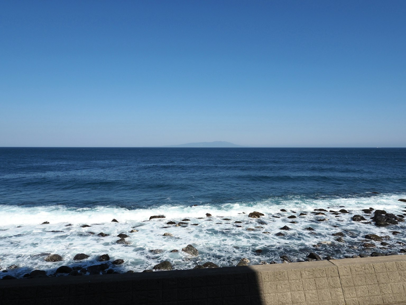 蓝色海洋的风景，温和的波浪拍打在岩石海岸上