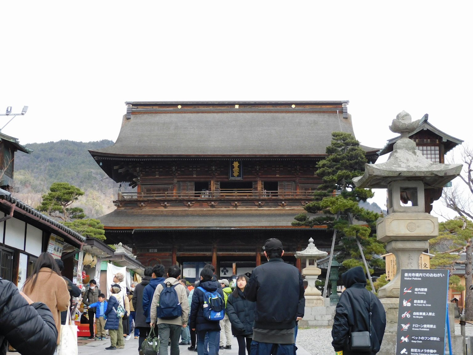 Crowd in front of a traditional Japanese building with stone lanterns