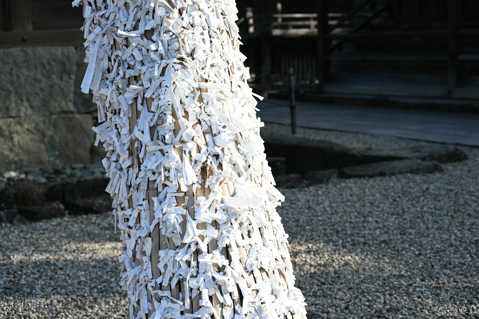 Árbol cubierto de tiras de papel blanco en un santuario