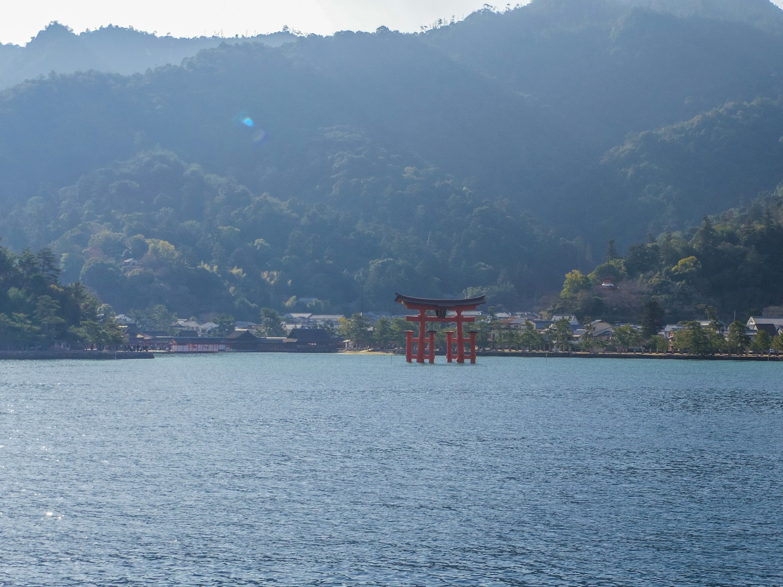 Torii rosso che si erge nel lago sereno circondato da montagne