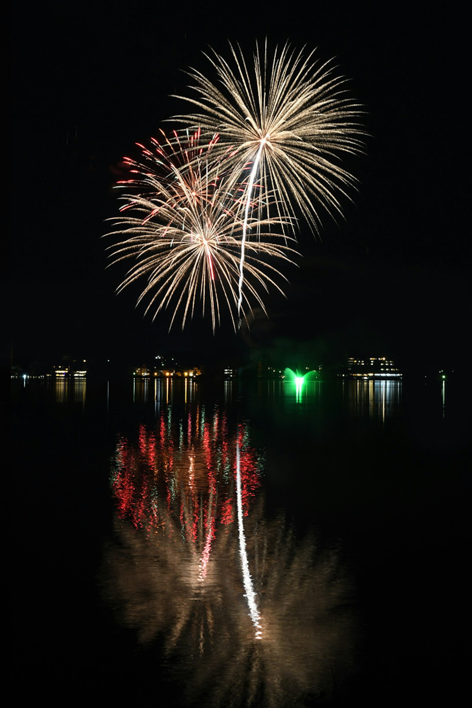 Colorful fireworks exploding in the night sky with reflections on the water