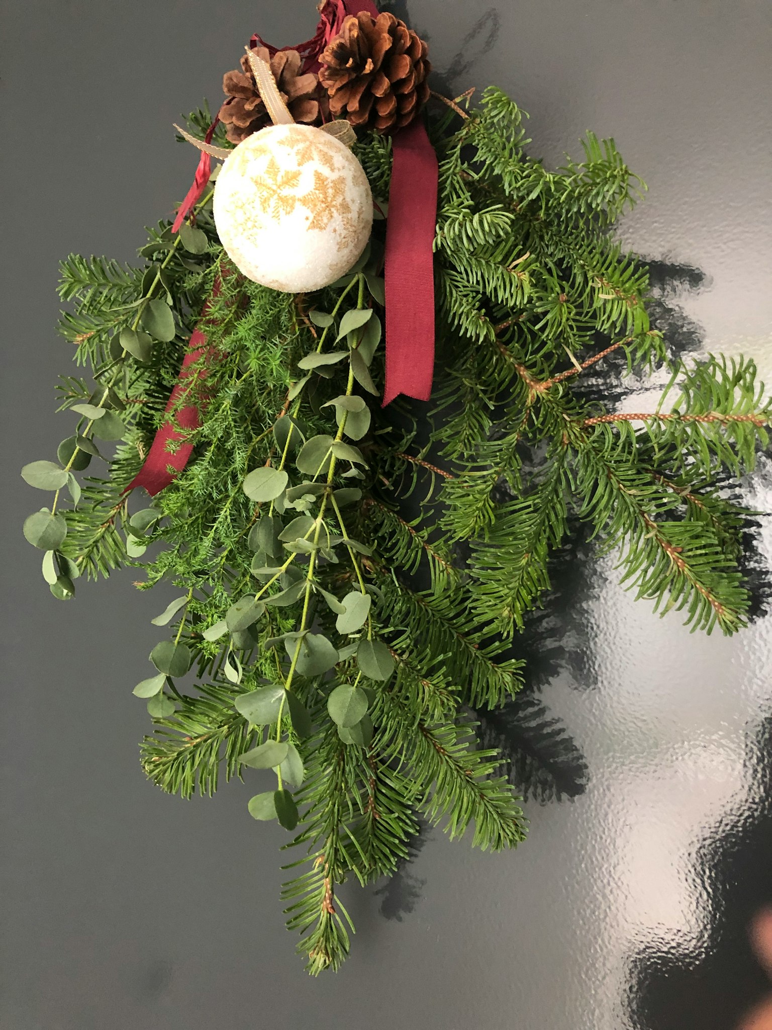 Weihnachtsdekoration mit grünem Laub Tannenzapfen rotem Band und weißem Ornament