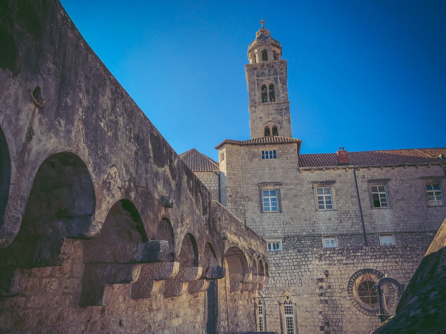 Bâtiment historique en pierre avec un clocher et des murs en arc