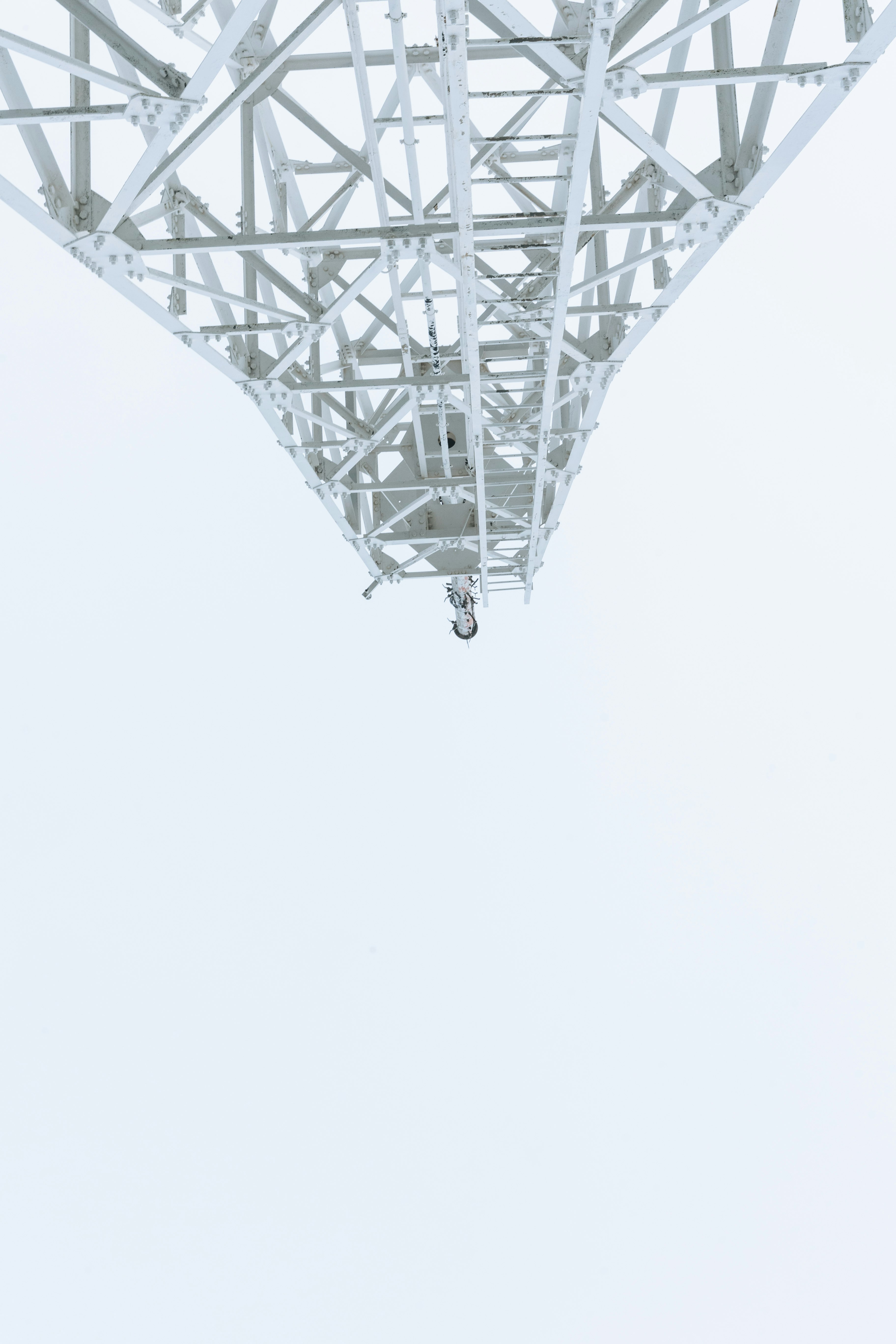 白い空に伸びる鉄骨の橋の下からの眺め