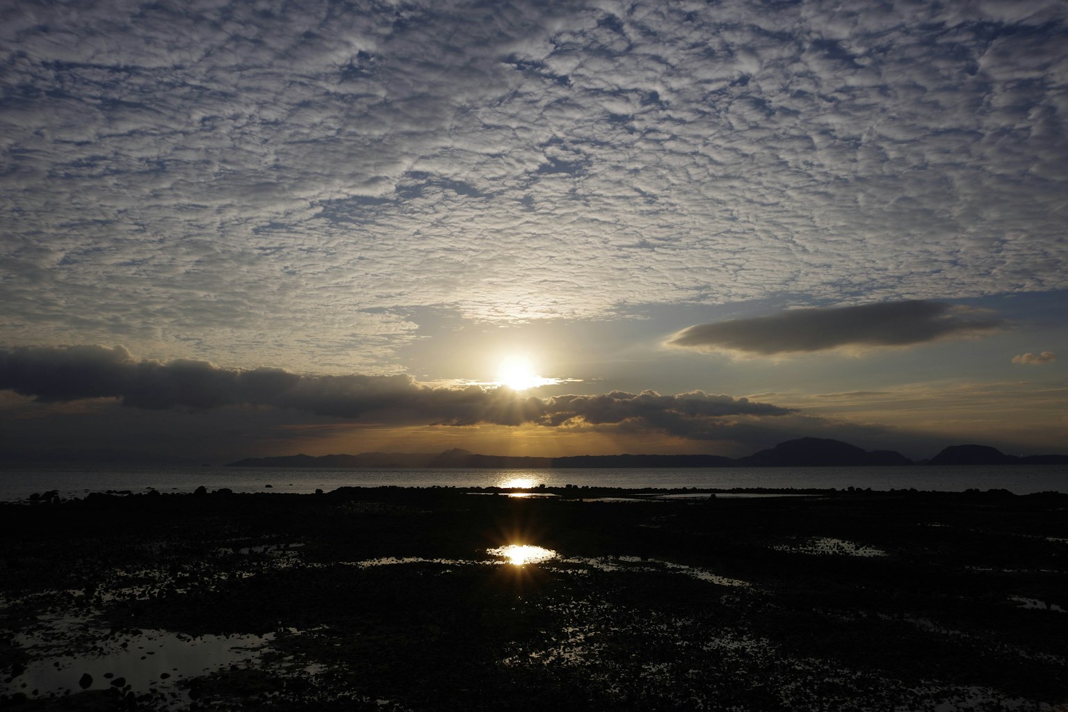 Beautiful sunset scenery with a cloudy sky calm sea and reflective water surface