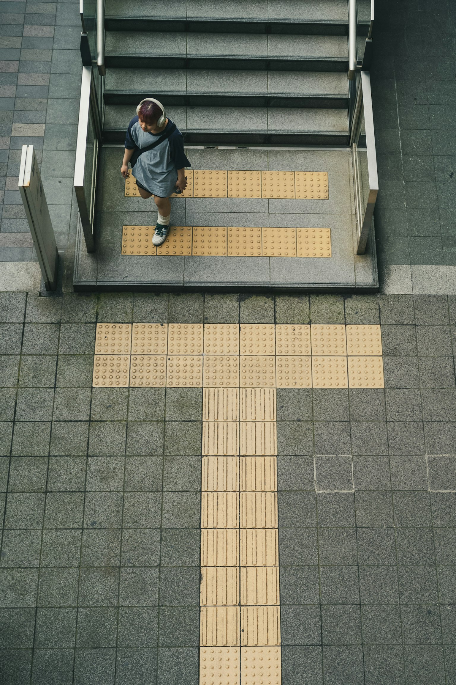 Person walking near stairs with yellow tactile paving