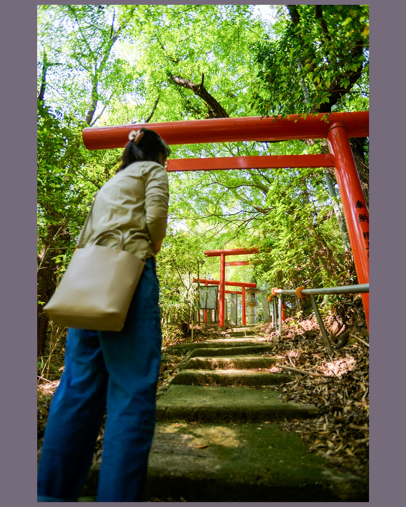 Frau, die einen Weg mit roten Torii-Toren umgeben von Grün betrachtet