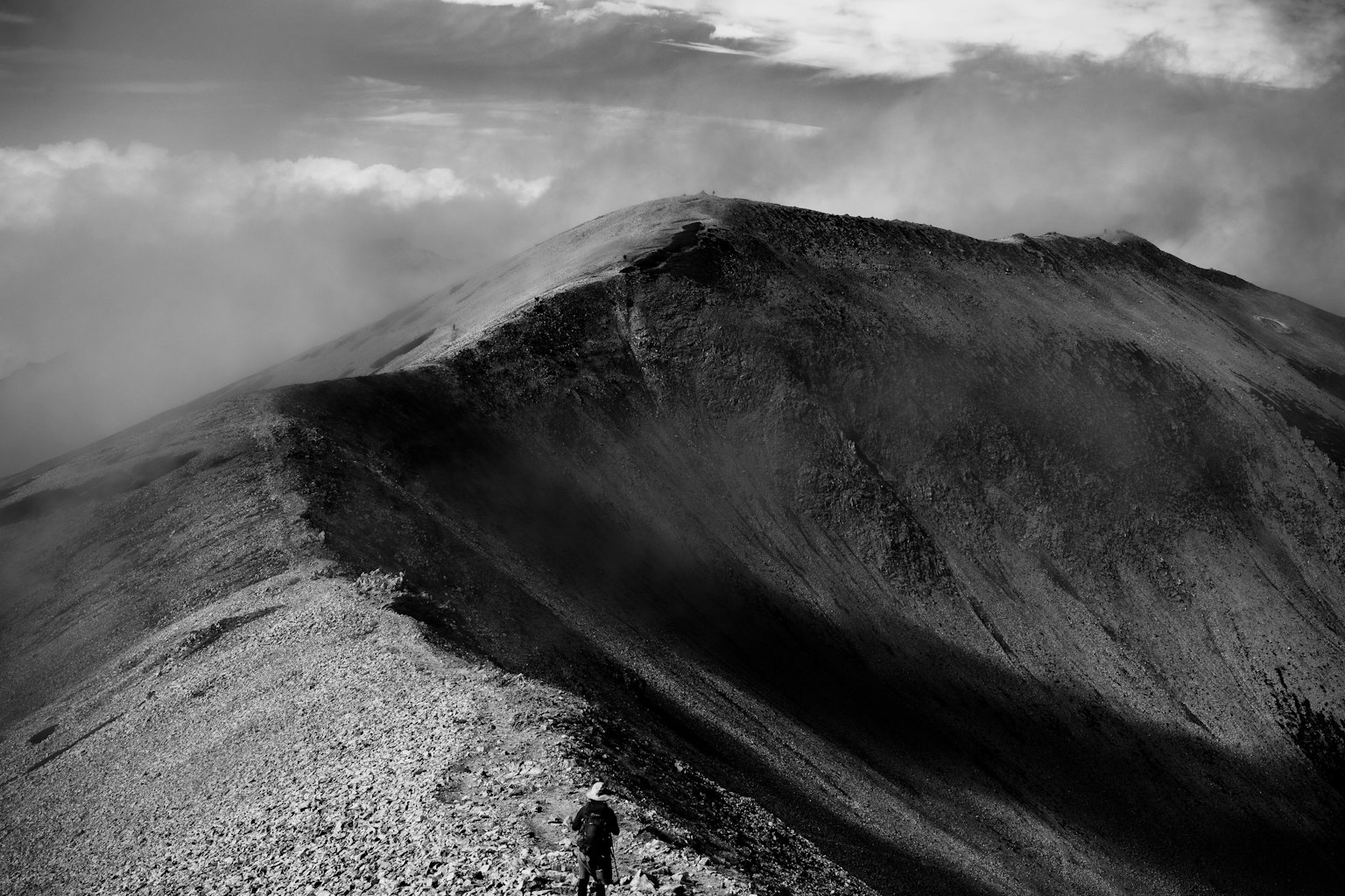 Silhouette eines Wanderers, der eine schwarz-weiße Berglandschaft erklimmt