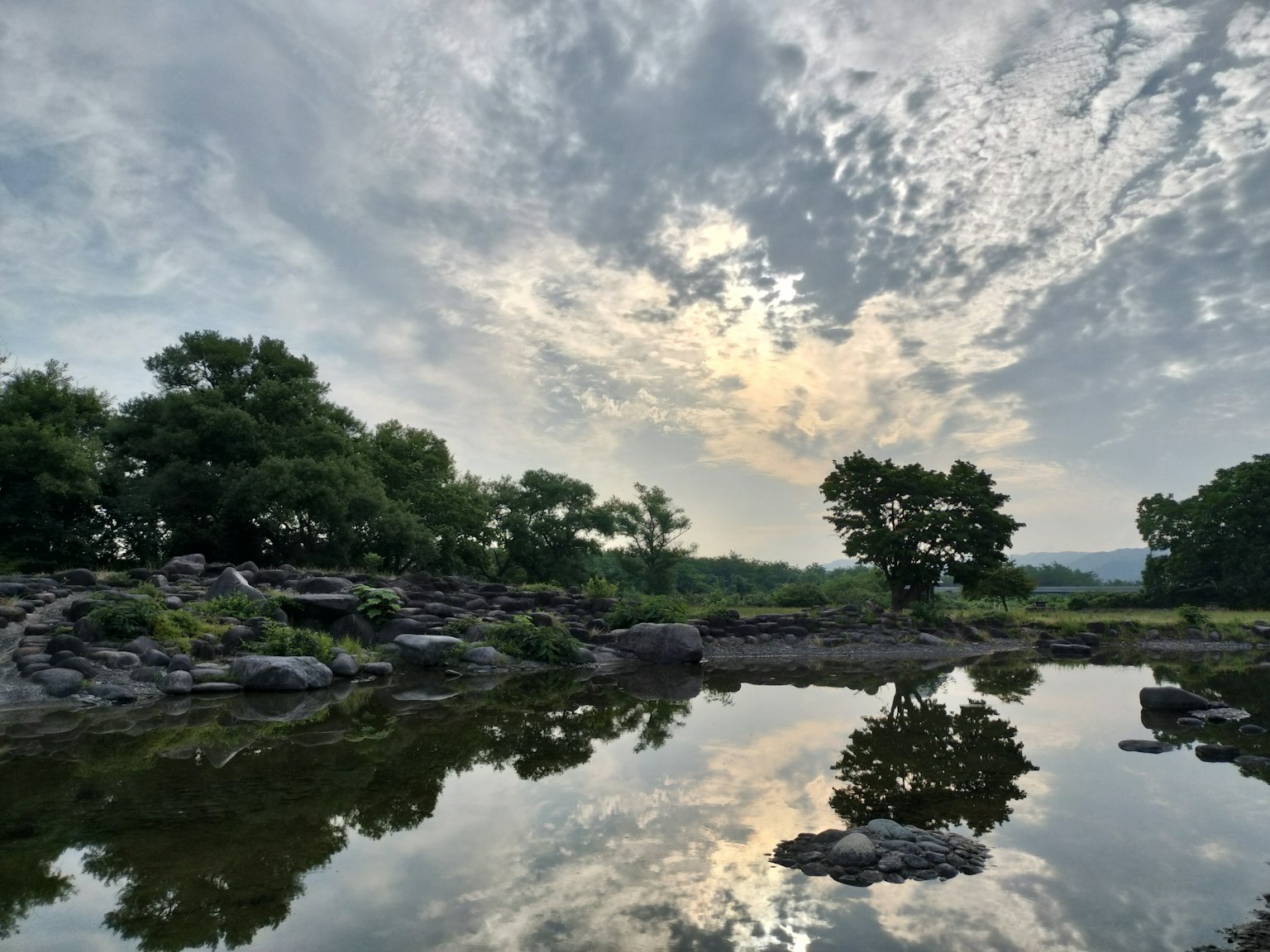 寧靜的景觀，樹木和雲彩在靜水中倒影