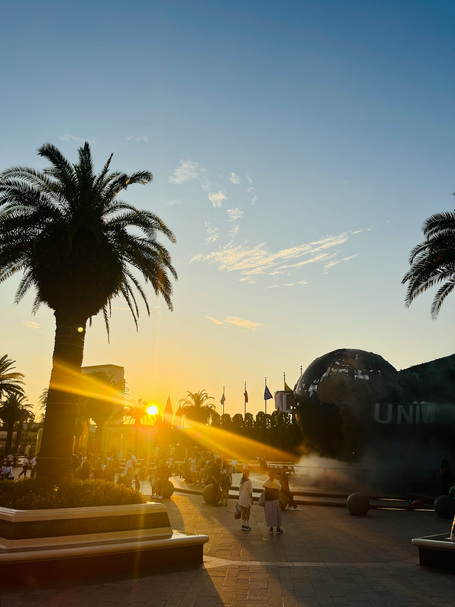 Silhouetten von Palmen und Menschen vor einem Sonnenuntergang