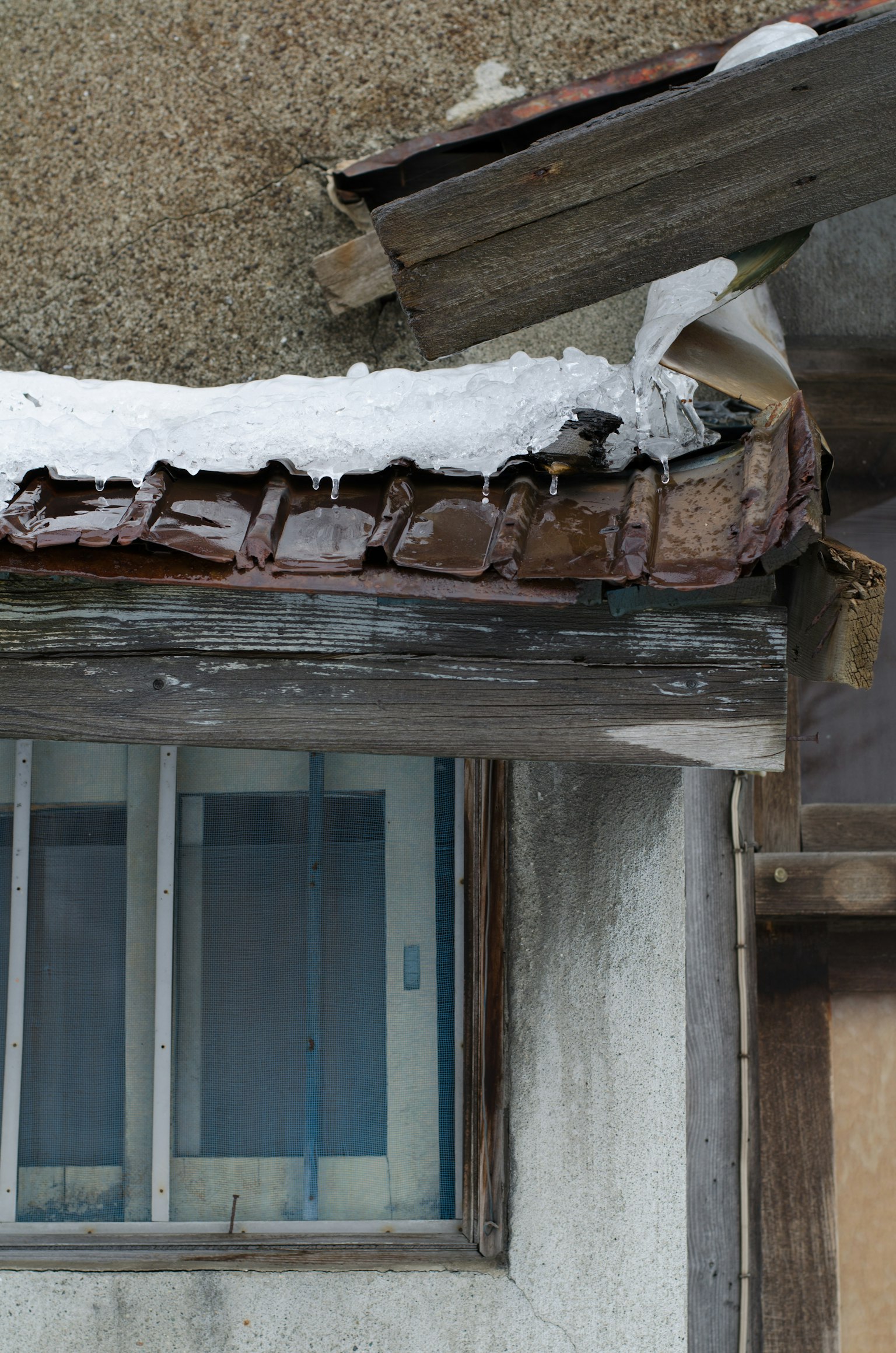 Toit d'une vieille maison avec de la neige et une fenêtre