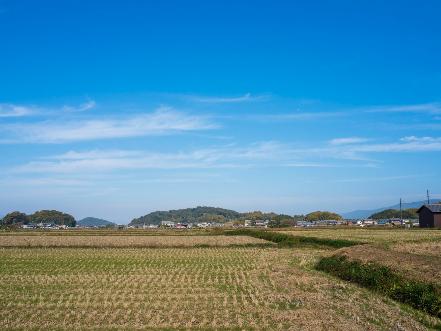 Paisaje rural bajo un cielo azul con siluetas de colinas