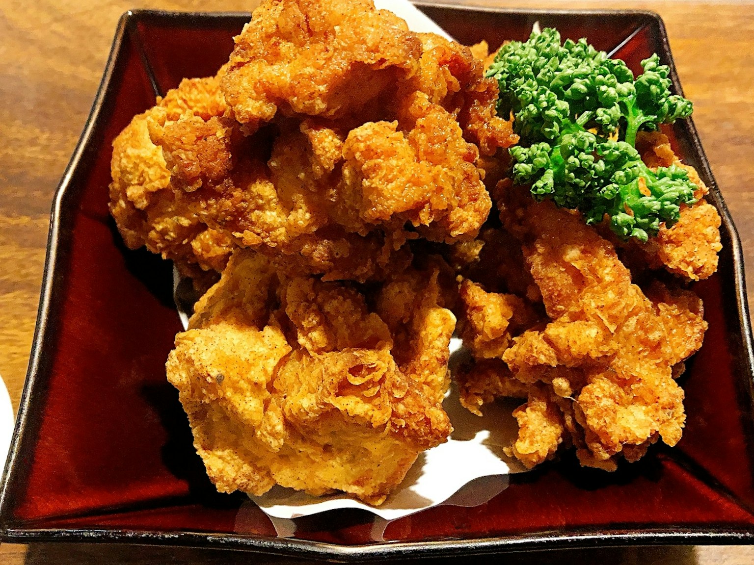 Plate of crispy fried chicken pieces with green garnish