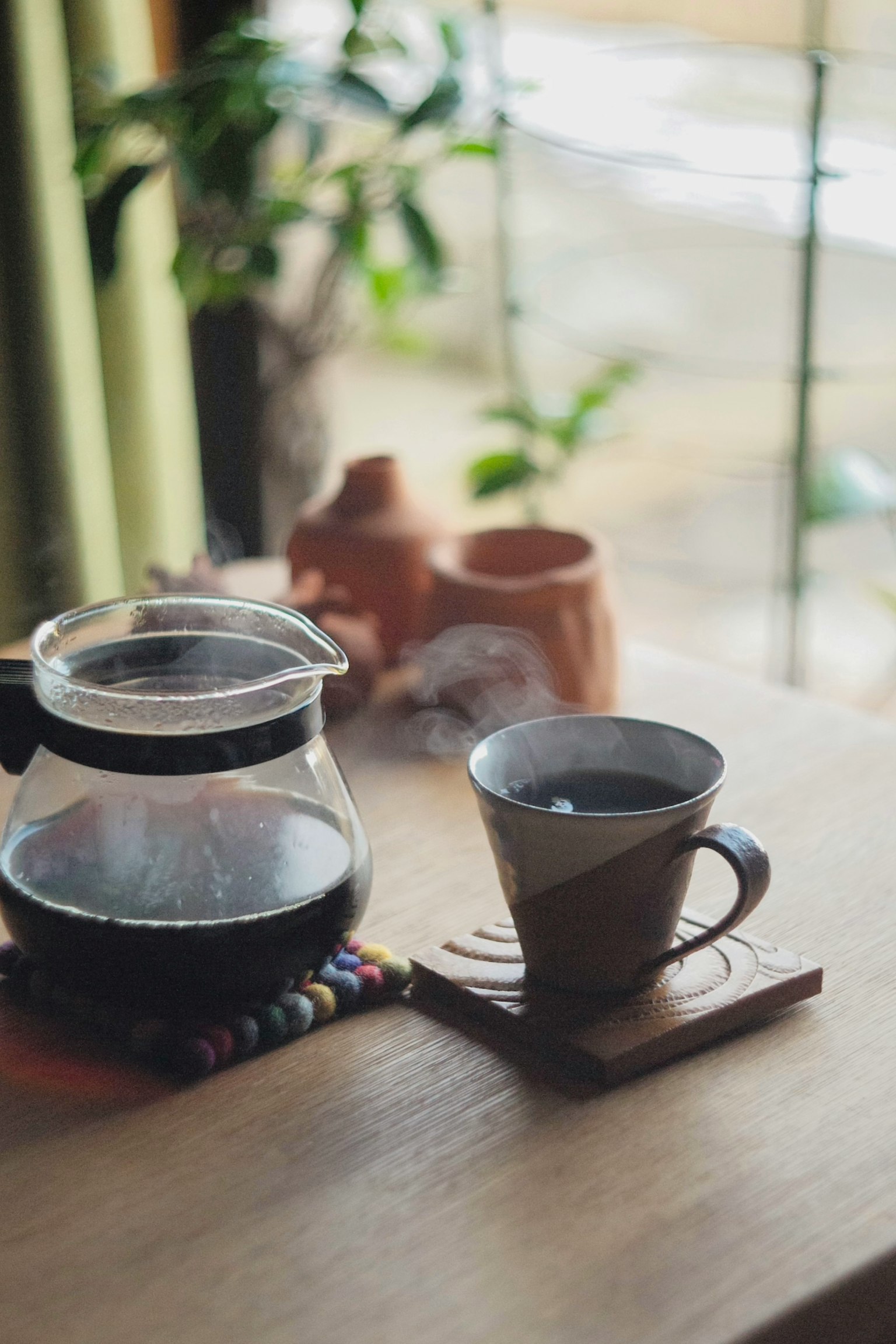 Cảnh yên bình với bình cà phê và cốc trên bàn gỗ