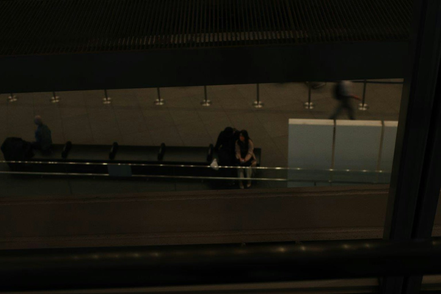 A young couple embracing on a busy train platform with people walking by