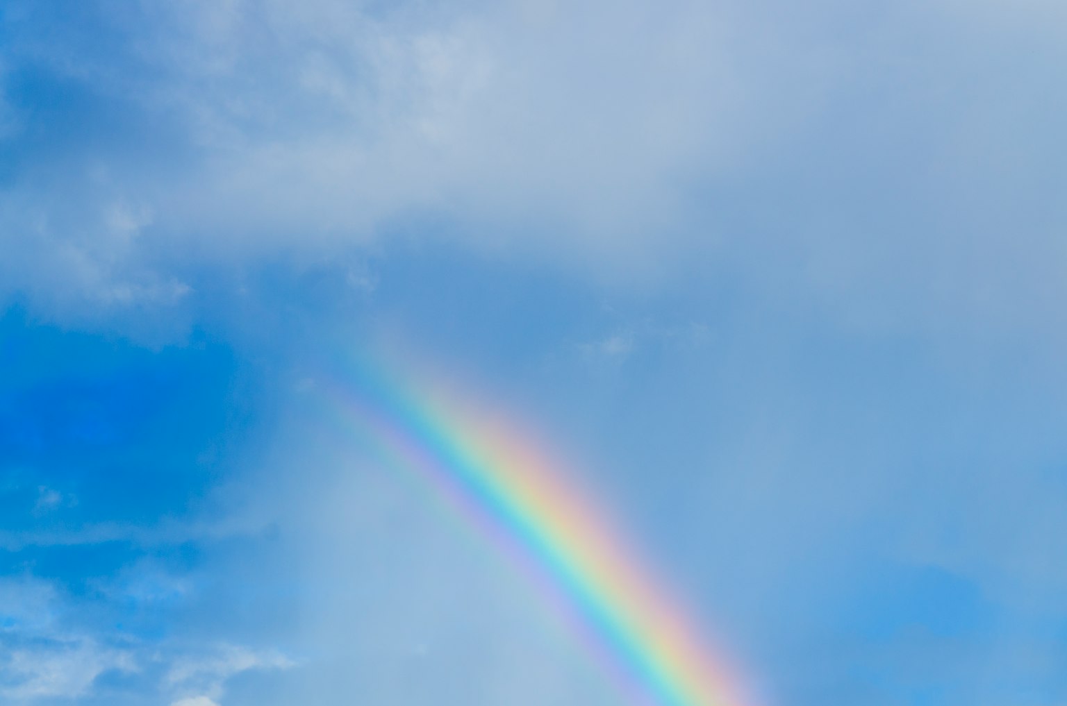 Un arcobaleno vivace che si estende su un cielo blu con nuvole