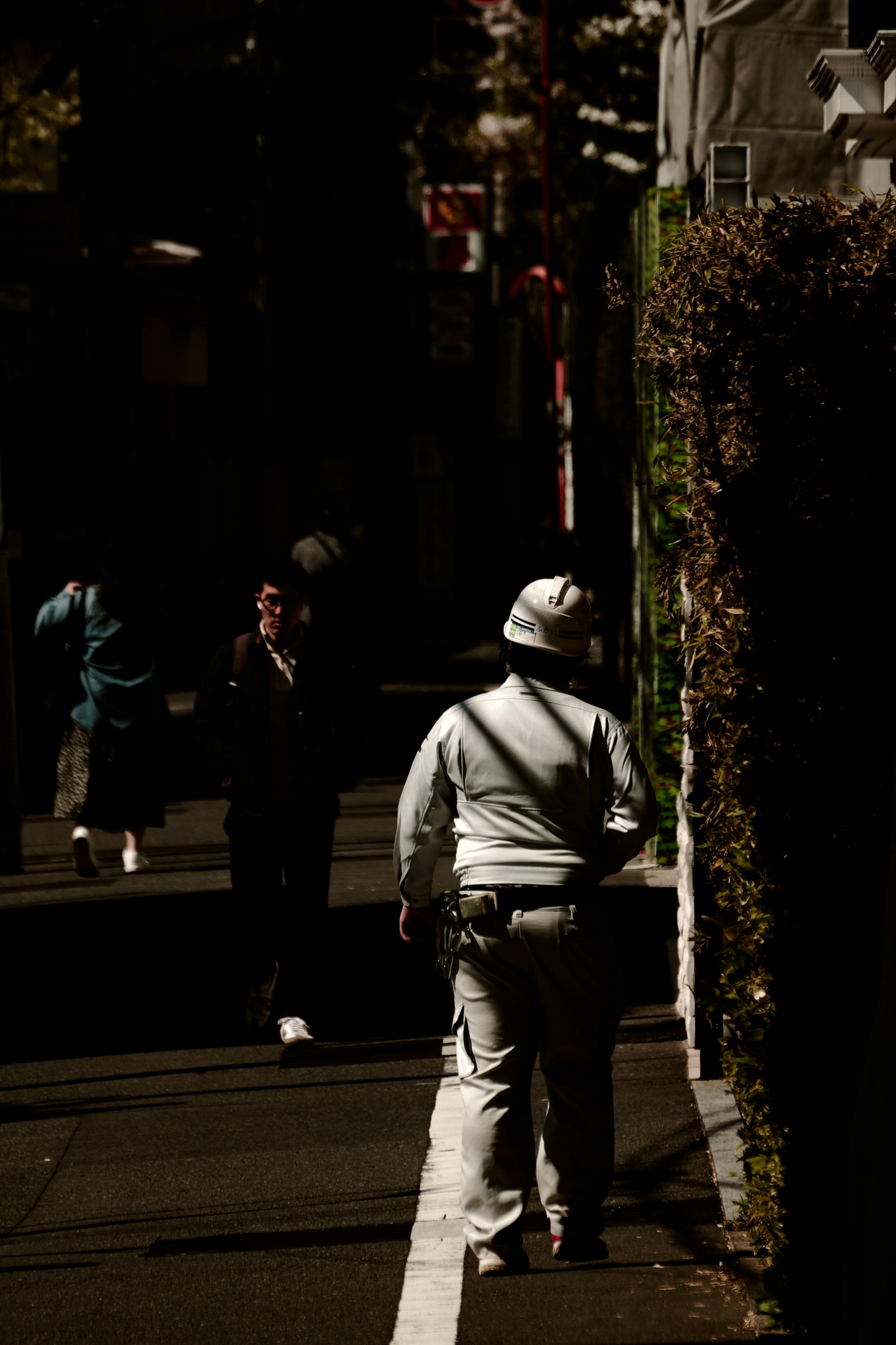 Personas caminando por una calle oscura con vegetación al lado