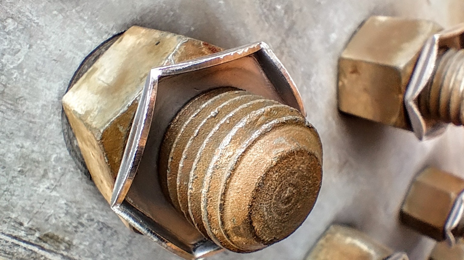Imagen en primer plano de un perno de metal mostrando perno y tuerca de color cobre