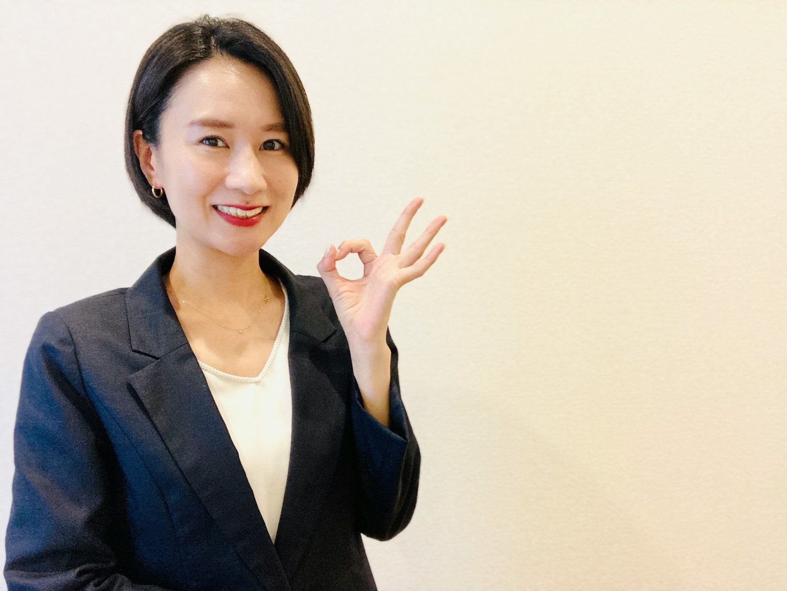 一位穿着商务西装的女性做出OK手势