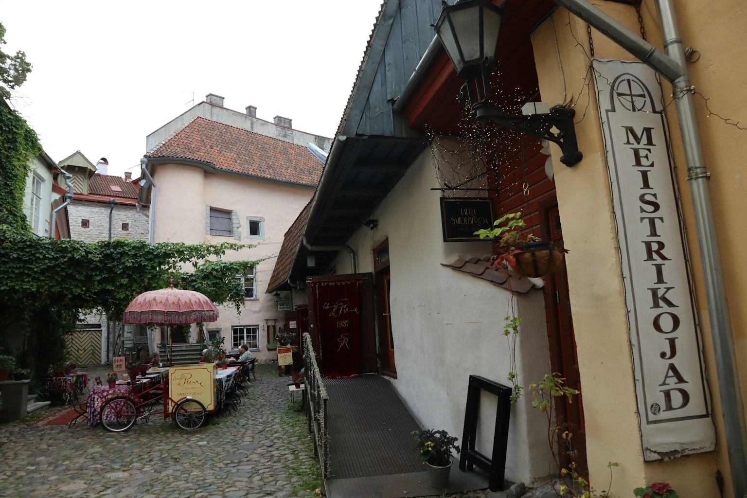 Charmante ruelle pavée avec la enseigne Meistrikojad et un parasol de café