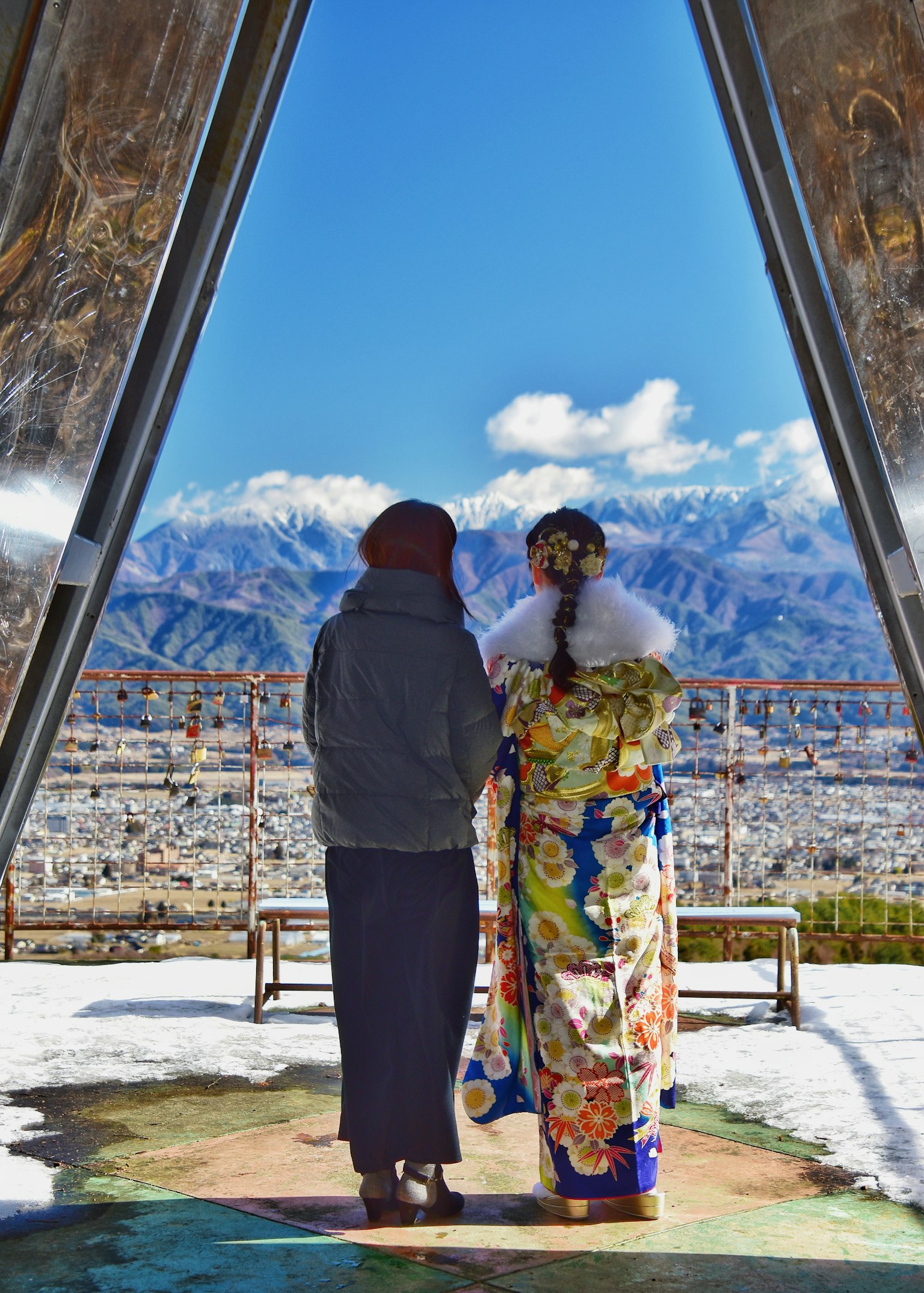 穿着休闲服的男人和穿着彩色和服的女人在雪景中与背景中的山脉站在一起
