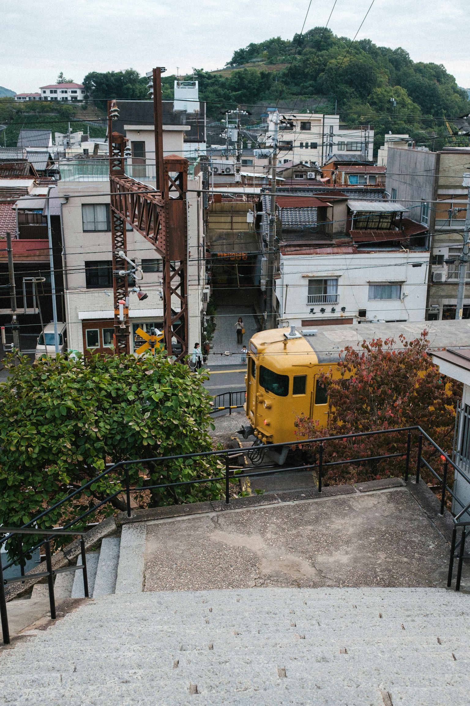 계단 아래에서 바라본 경치 노란 기차와 주택가가 보인다