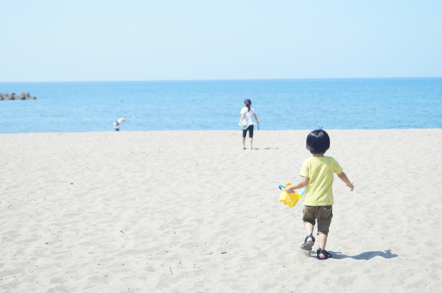 Un bambino che cammina sulla spiaggia di sabbia verso l'oceano