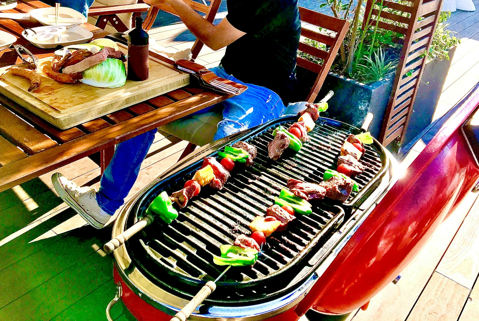 Sate berwarna-warni dipanggang di pemanggang merah di pengaturan teras