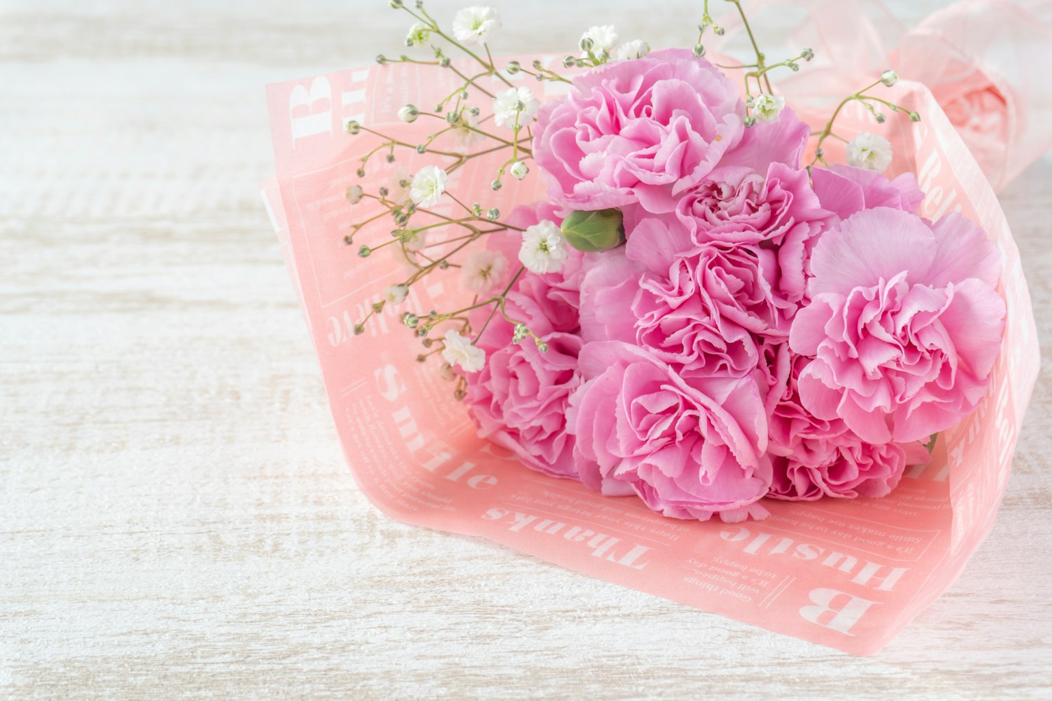 Ramo de claveles rosas envuelto en papel rosa claro