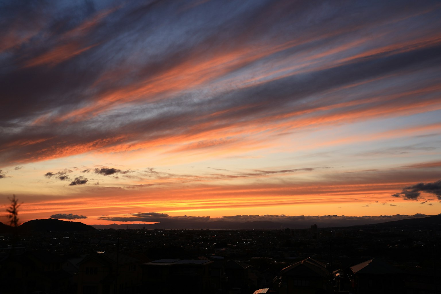 Beeindruckender Sonnenuntergangshimmel mit orangefarbenen und blauen Streifen am Horizont