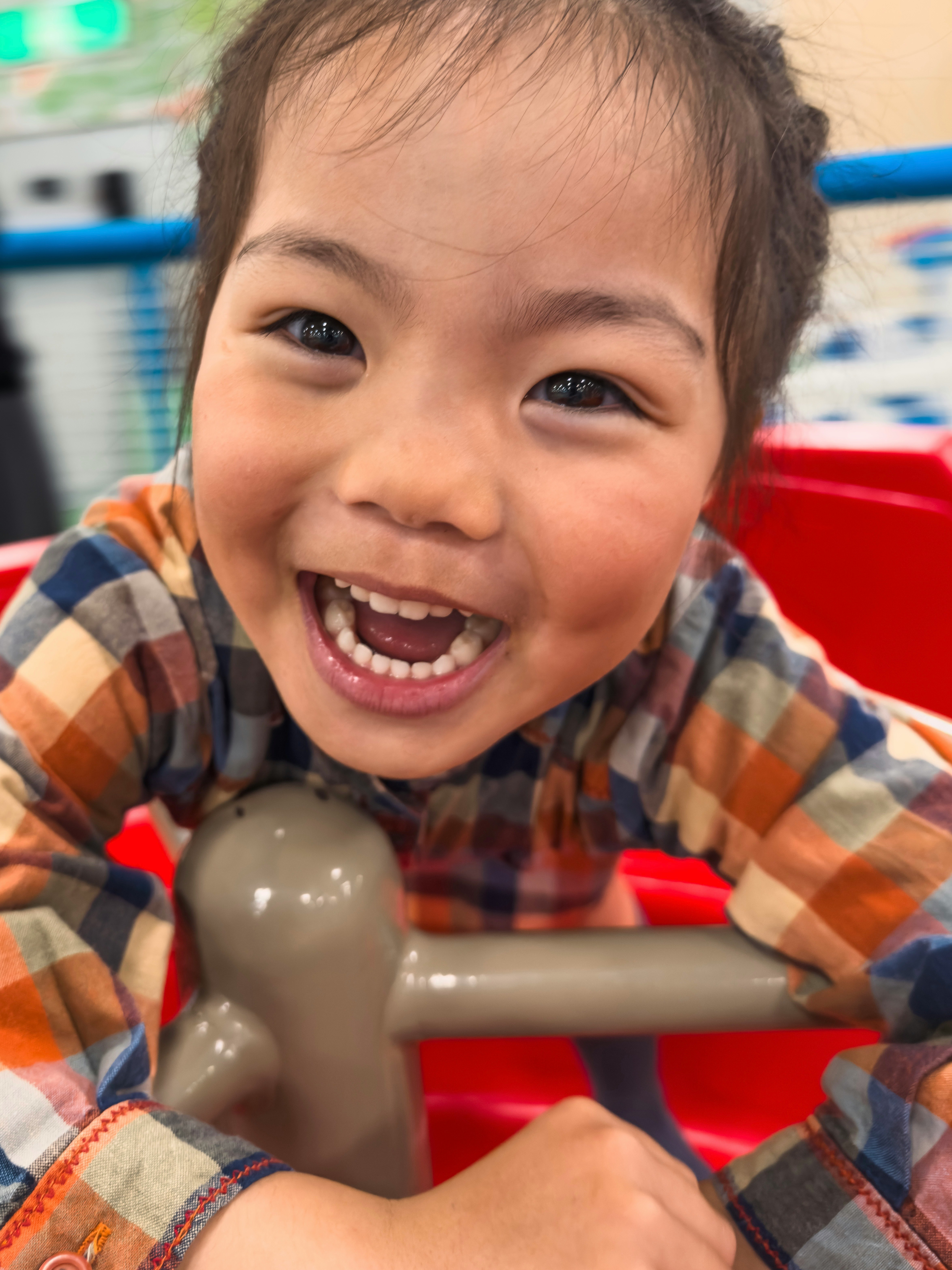 赤い椅子で笑顔の子どもが手を伸ばす室内の一瞬