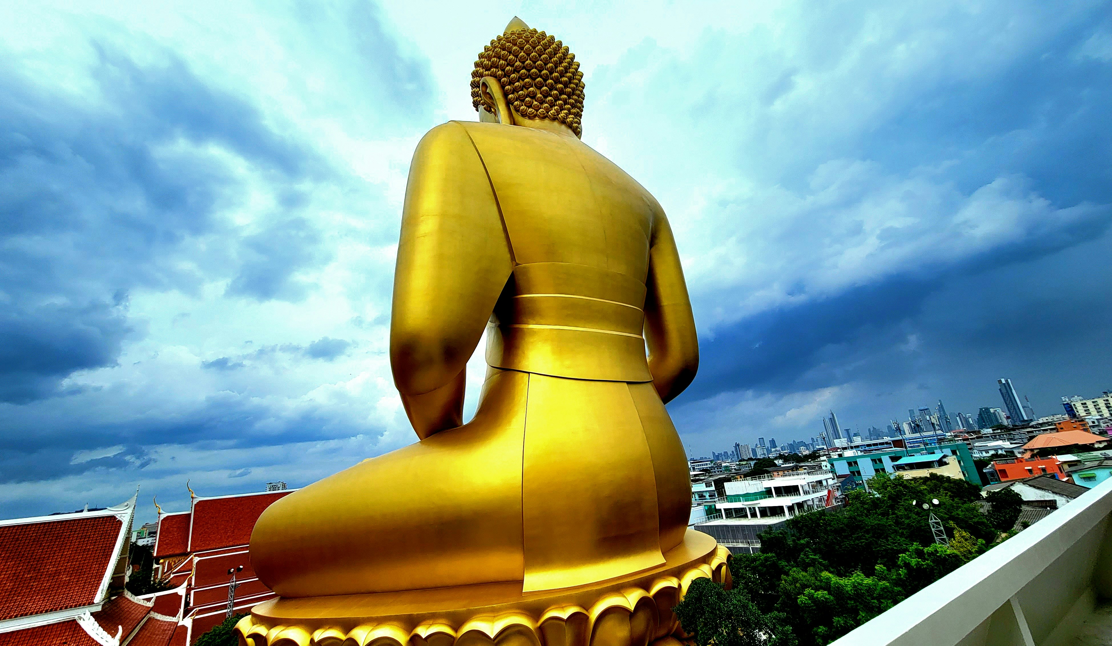 รูปปั้นพระพุทธสีทองกับทิวทัศน์เมืองใต้ท้องฟ้าสีคราม