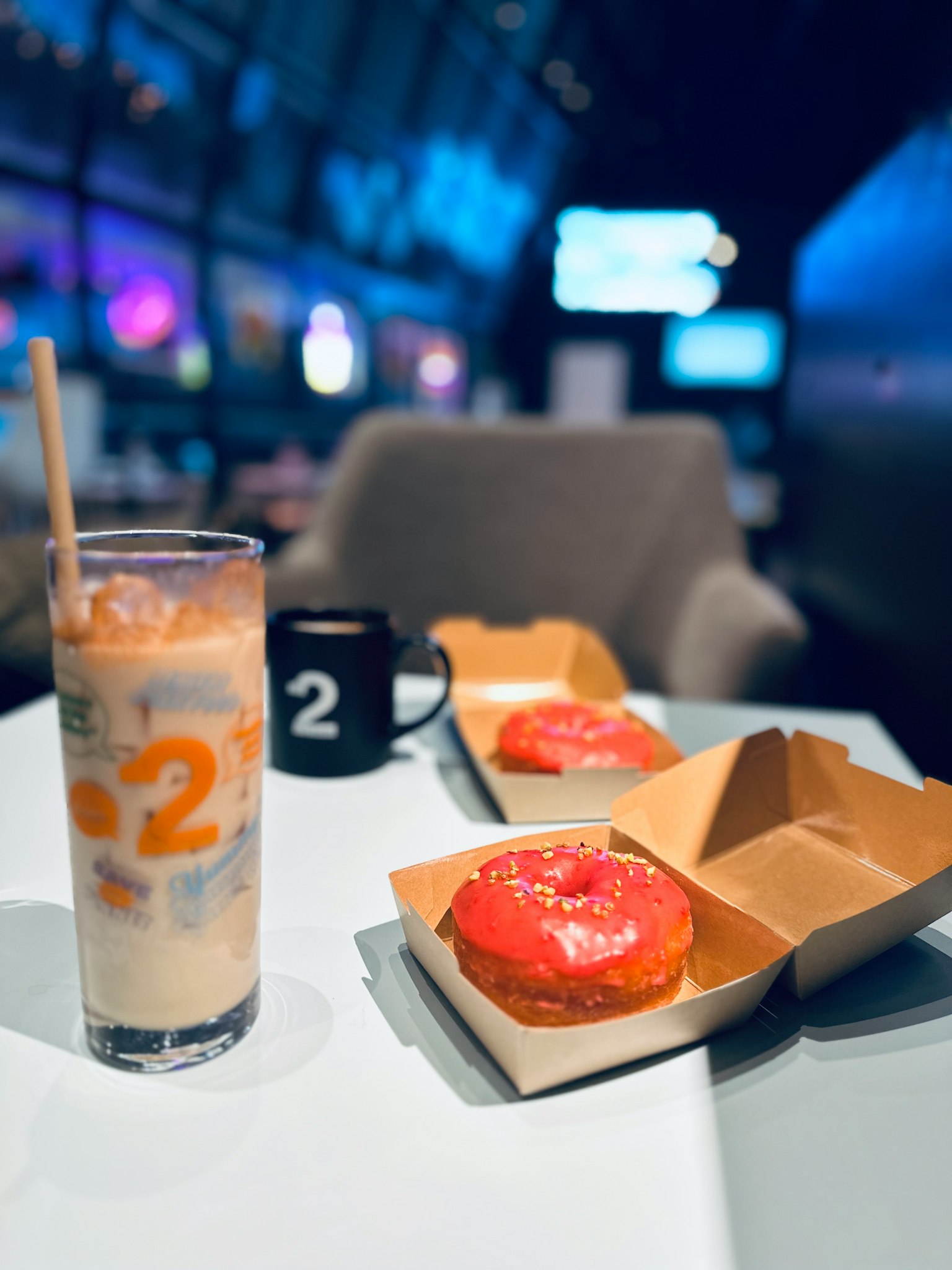 Donat berwarna dan kopi es di meja kafe modern
