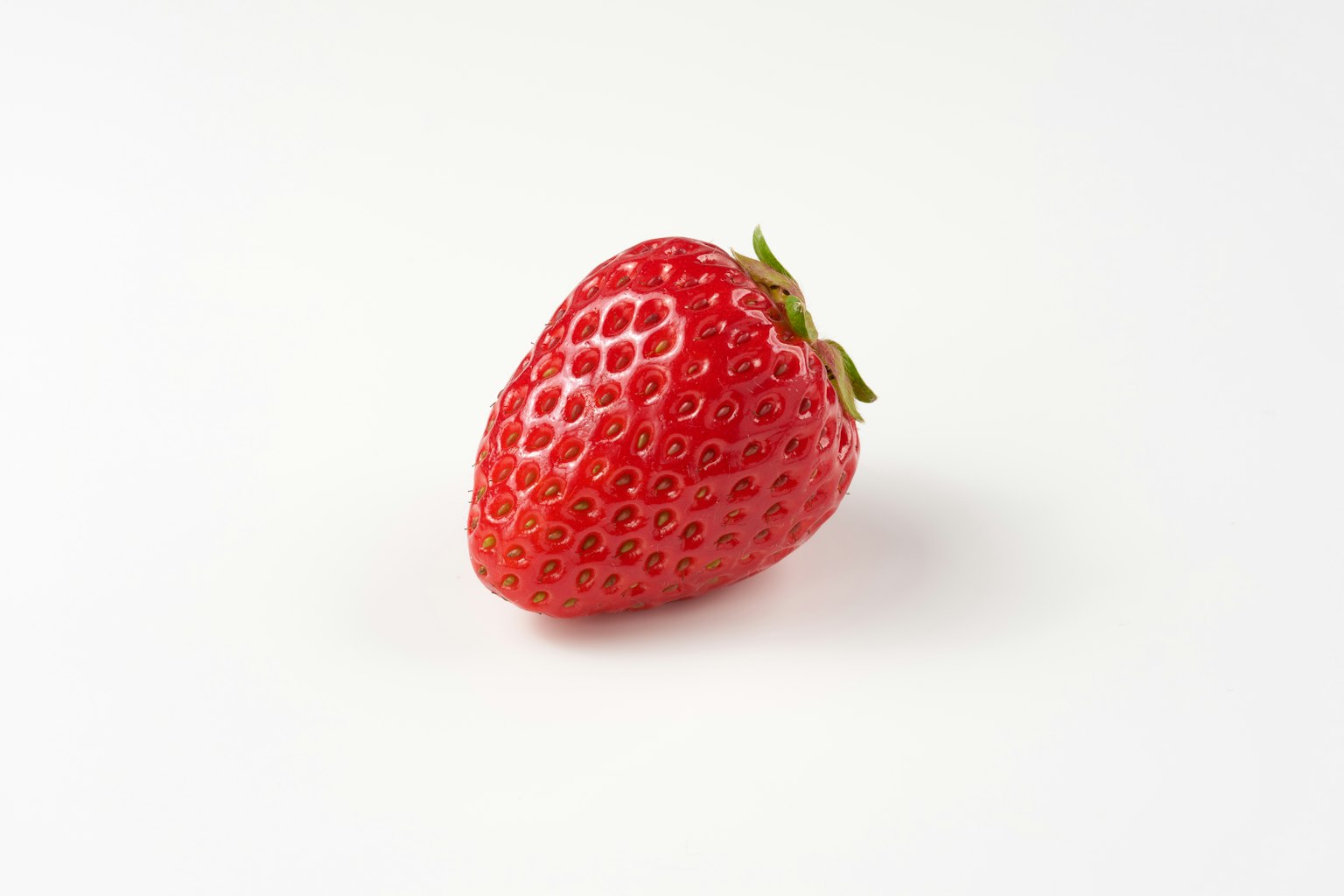 Una sola fragola rossa su uno sfondo bianco